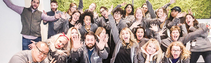 A group of employees wearing Duo clothes, smiling, and showing their hands to the camera